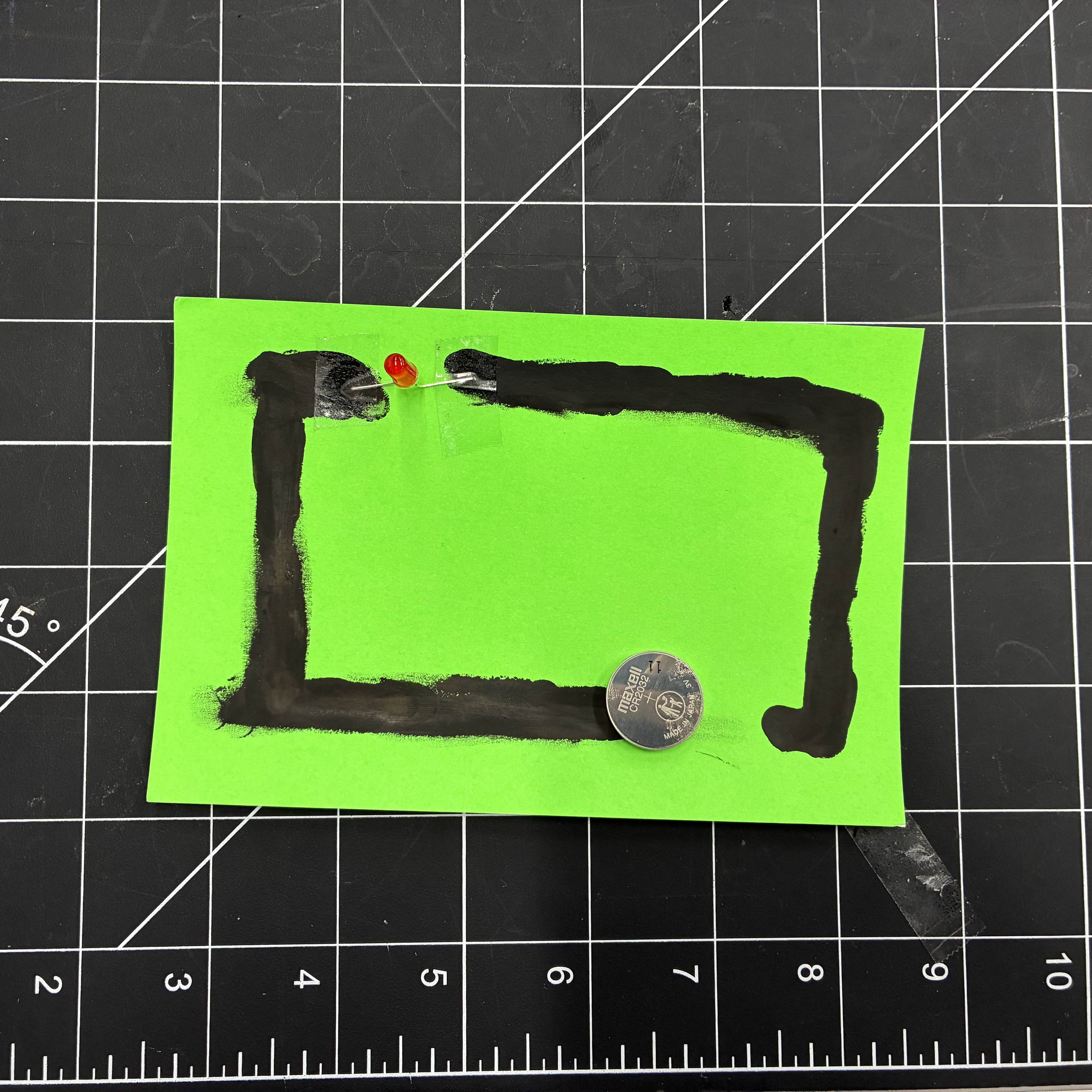 This is the rectangle made of conductive paint. I taped an LED light to fill the gap in the rectangle and then placed a battery on the other end.