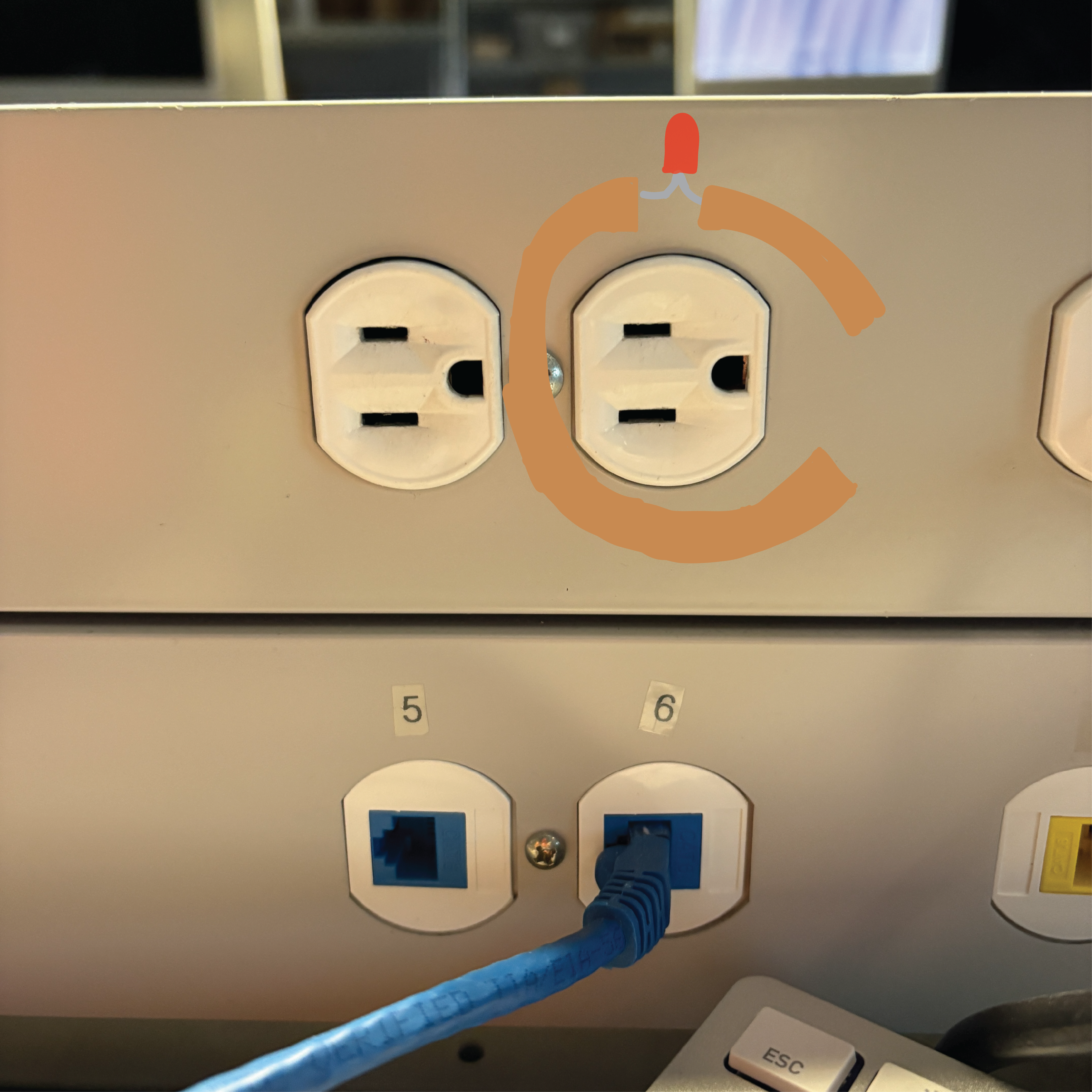 This is one of the outlets that are connected to the desks in the AA1A classroom. There is copper tape put around the outlet with an LED light connected to it and a space in the tape for the battery..