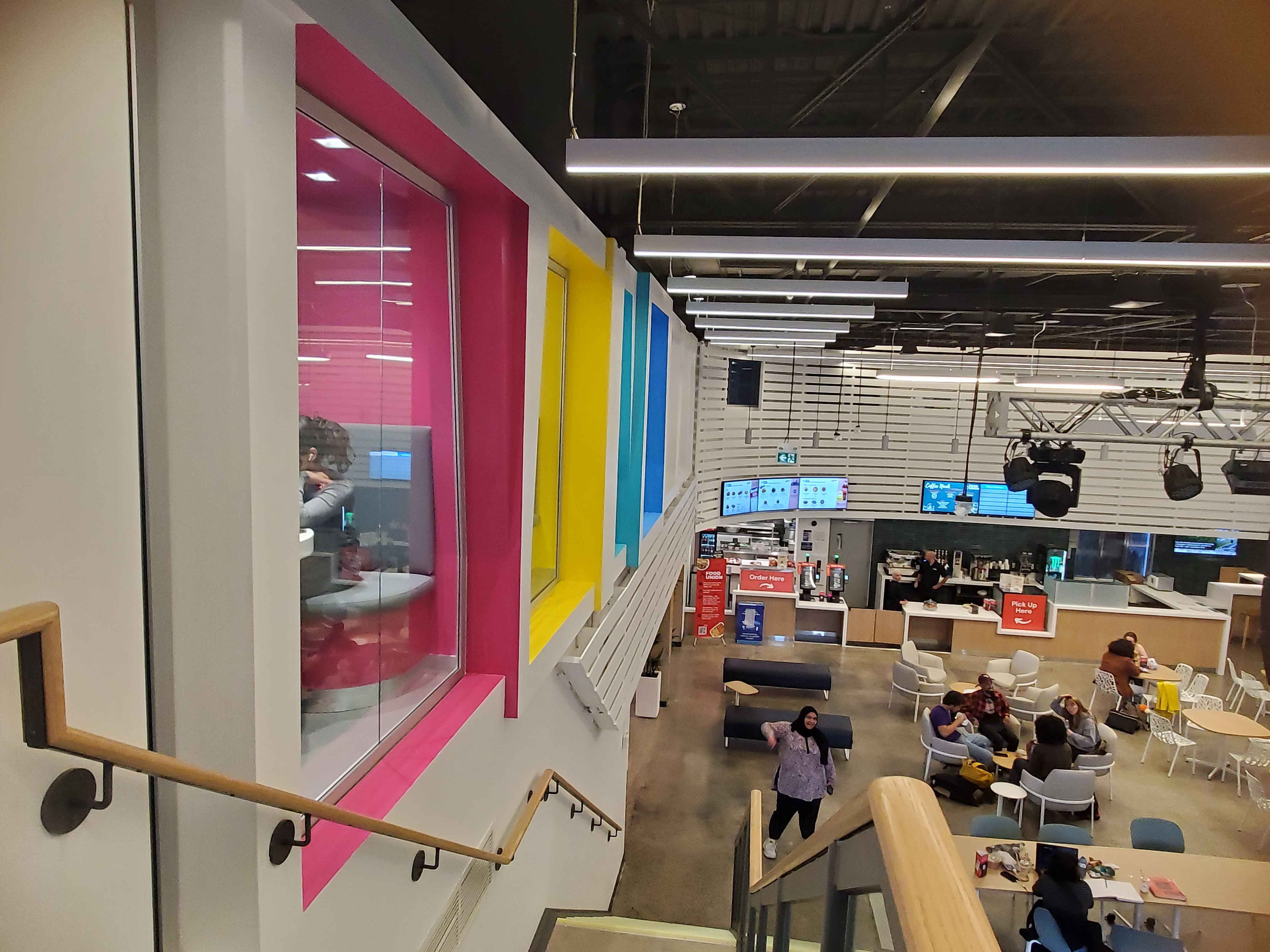 This is an area in the marquee where you can walk up the stairs and see seating areas that are multiple different colours. The design consists of wooden stairs to contrast the concrete and colours in each seating area to create a focus on those spots.
